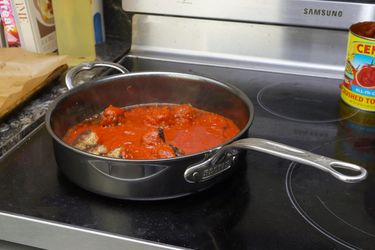 a saute pan filled with tomato sauce and meatballs