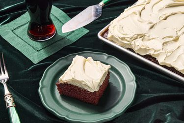 piece of guinnes chocolate cake taken from corner of sheetpan and placed on a green plate. Side of beer on green napkin, green fork, on top of green fabric