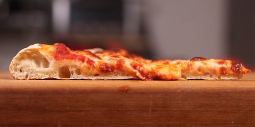 Cross-section of New York-style pizza slice with crust made from dough kneaded in food processor, showing airy, well-developed texture.