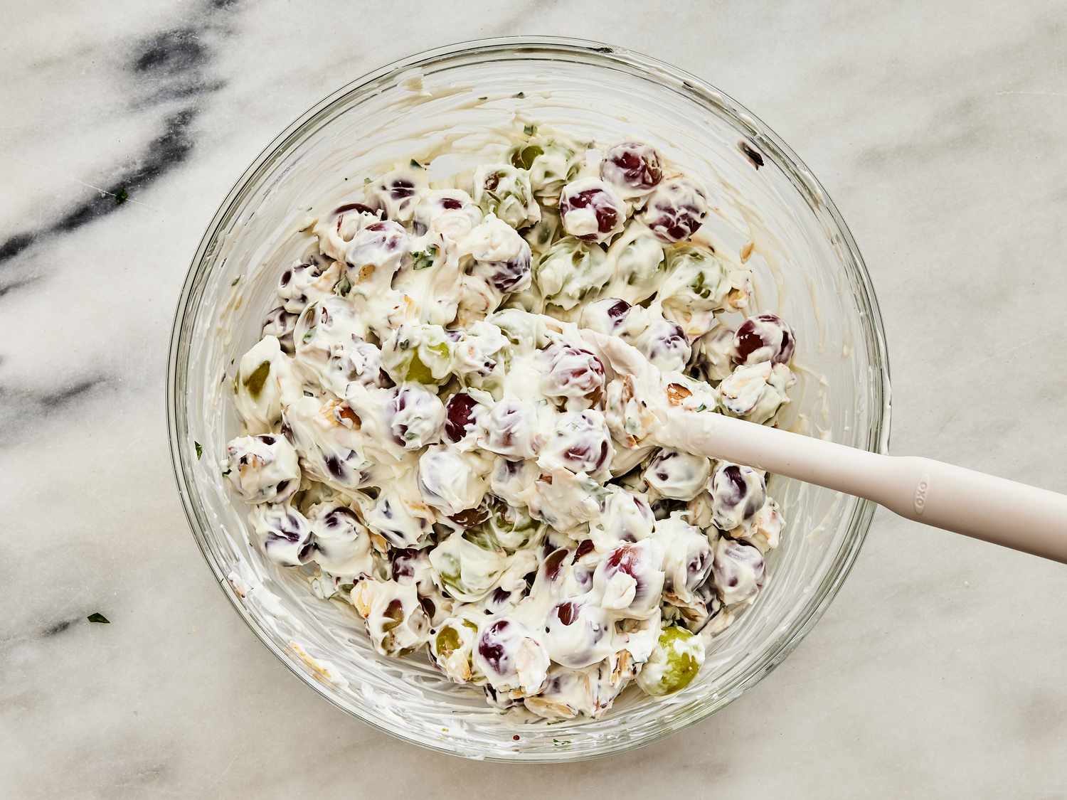 Mixing dressing and ingredients together in a glass bowl with a spoon 