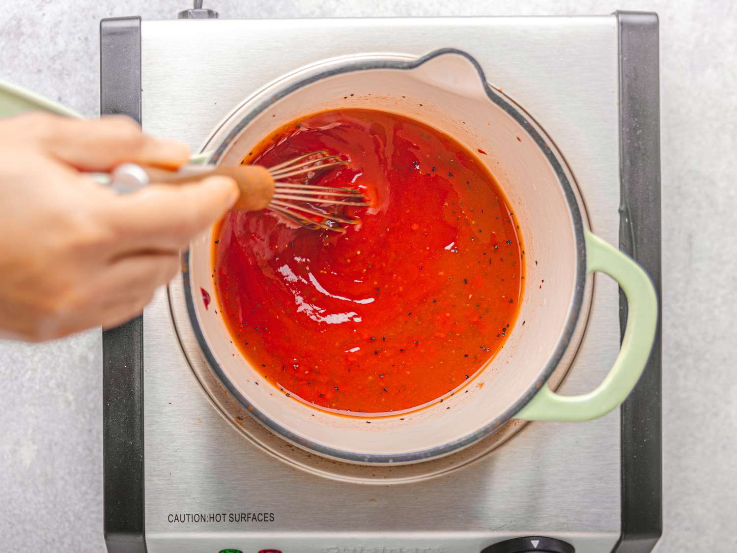 Sauce being prepared in a pot using a whisk on a stovetop