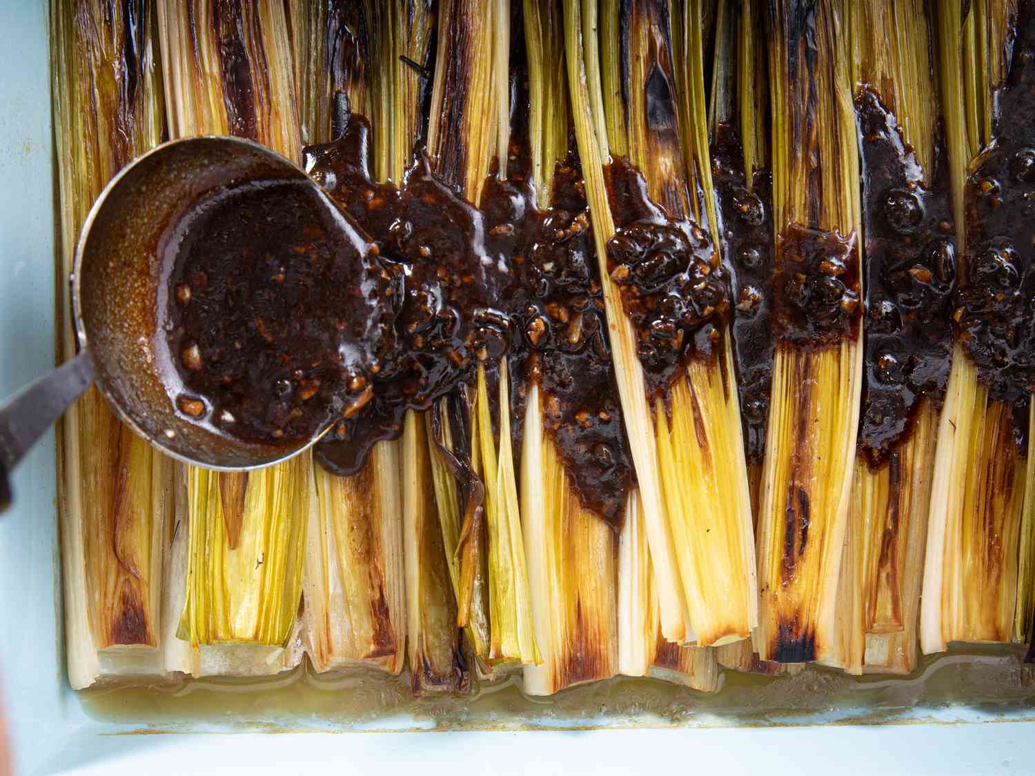 Overhead view of pouring sauce on leeks