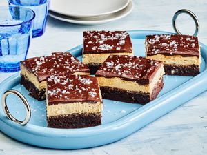 Buckeye Brownies with sea salt garnish, cut into pieces on a blue dish, with blue cups and small white plates 