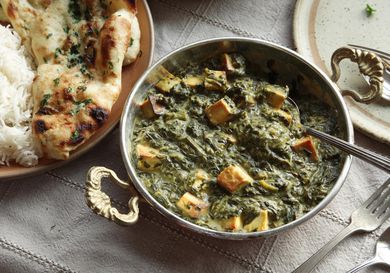 A metal dish filled with vegan saag paneer made with tofu