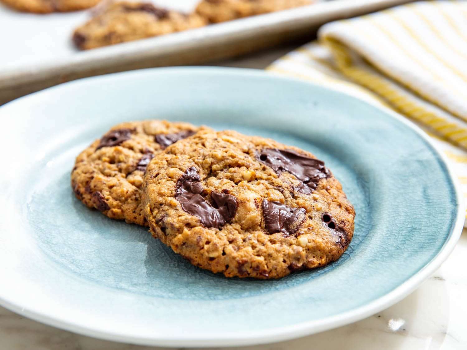 Side view of two oatmeal chocolate chip macadamia nut cookies on a blue plate.