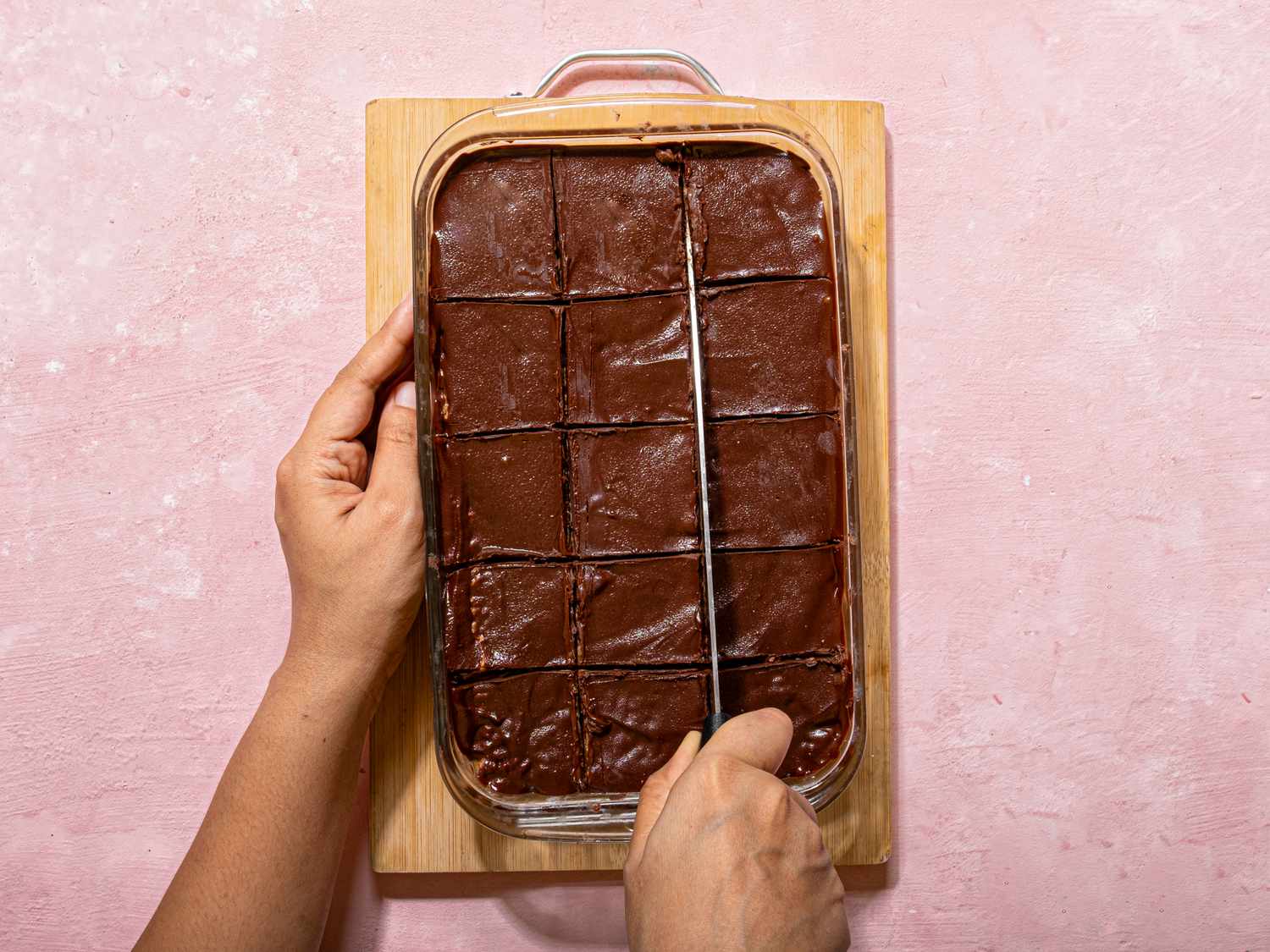 A tray of frosted bars being sliced with a knife on a wooden board