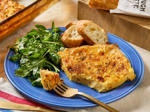 A plate with a serving of eggbased casserole side salad and slices of bread