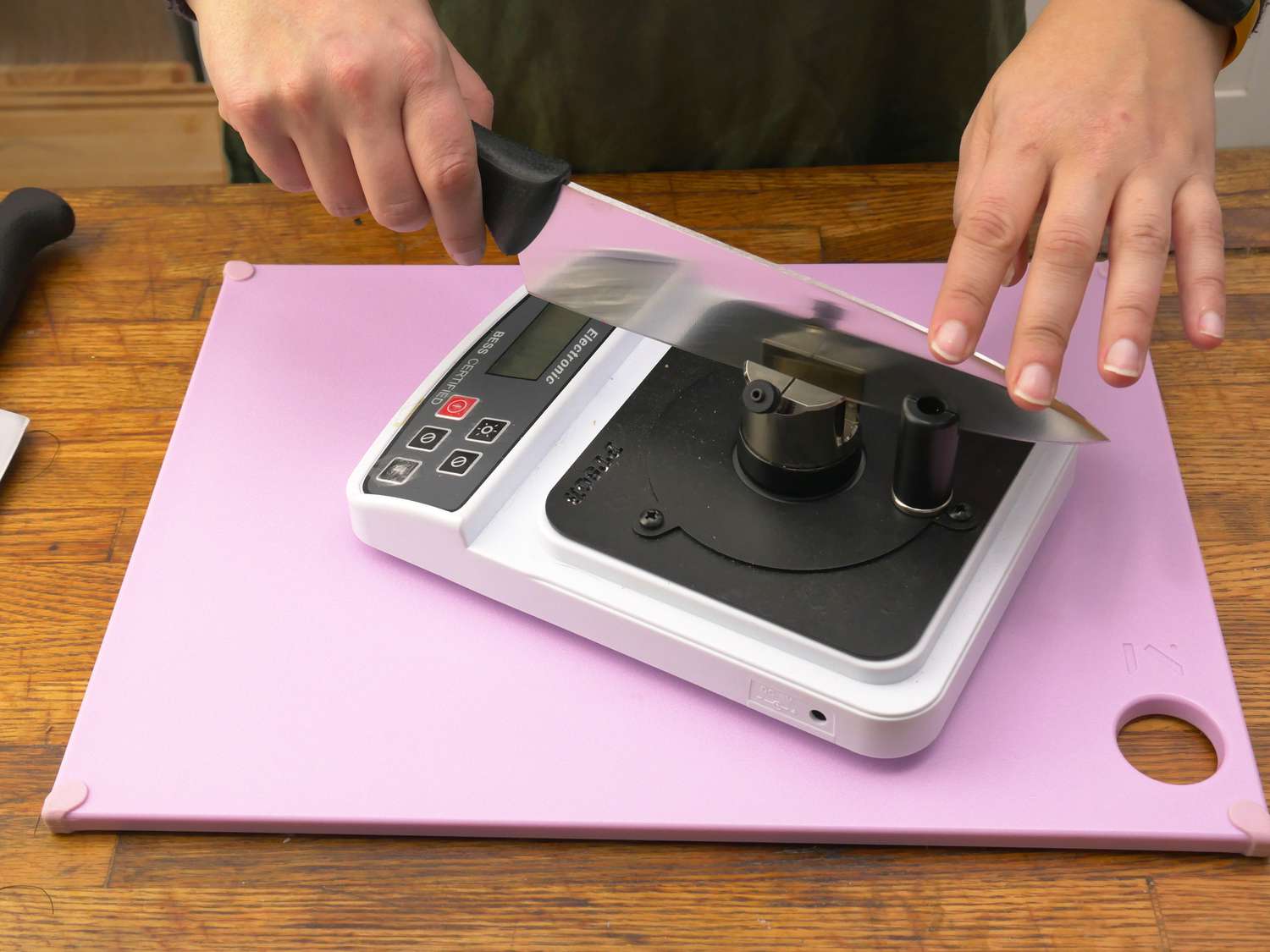a person using a knife sharpness measurer to take the sharpness of a chef's knife