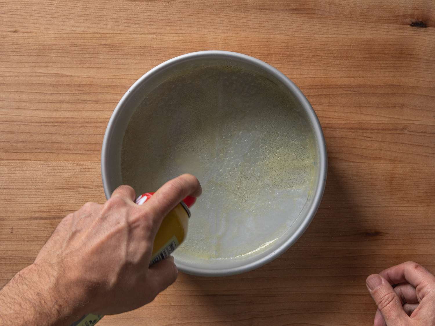 Spraying an 8-inch cake pan layered with a parchment round with nonstick cooking spray