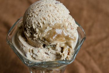 Two scoops of pecan pie ice cream, served in a parfait glass.