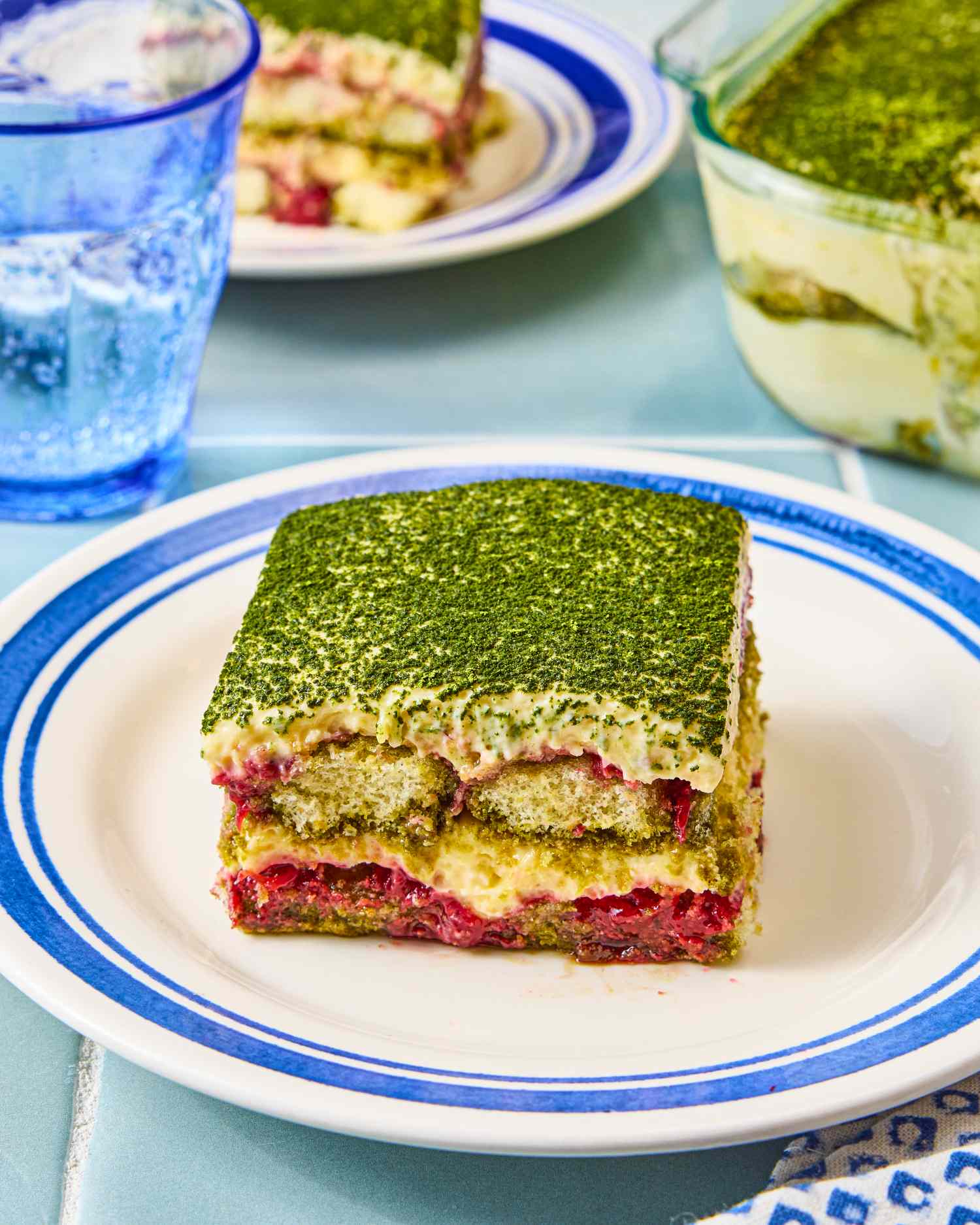 A serving of strawberry matcha tiramisu on a white plate with a blue border