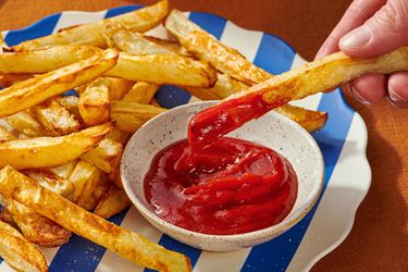 French fries dipped into ketchup on a plate