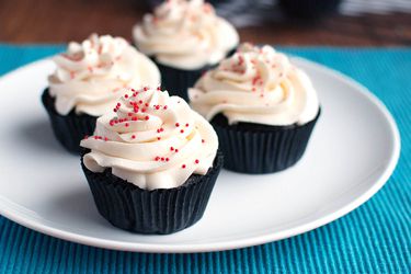 Four buttercream cupcakes resting on a white plate