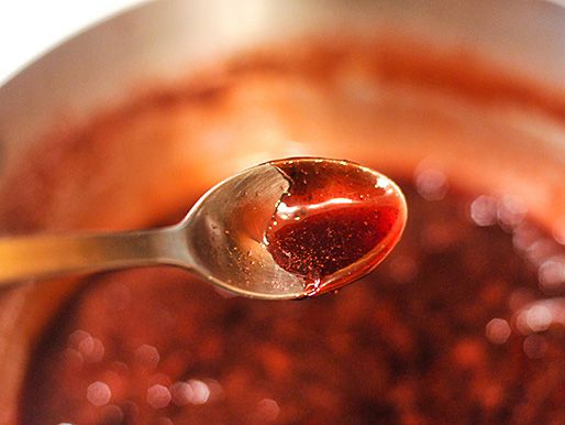 Closeup of a spoon covered in ruby-red Cumberland sauce.