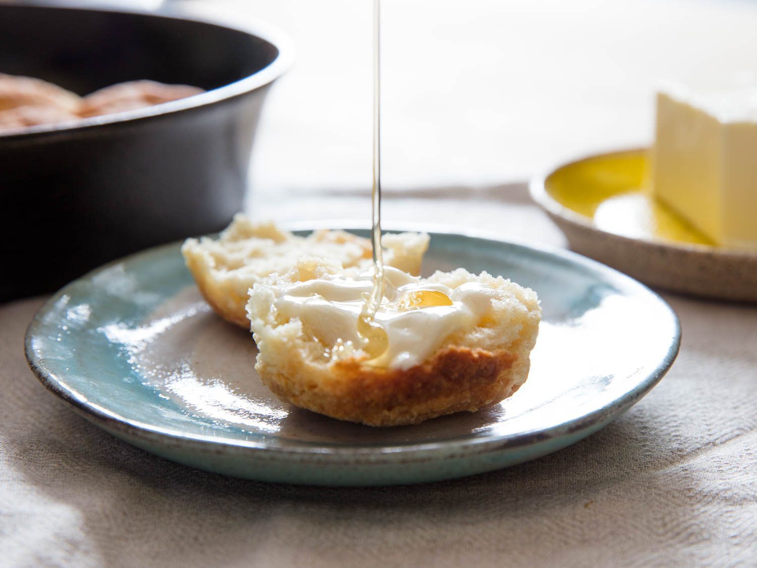 Honey drizzling on butter melting on split biscuit.