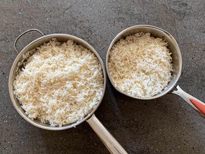 Two pots filled with cooked rice one large and one smaller placed on a dark surface