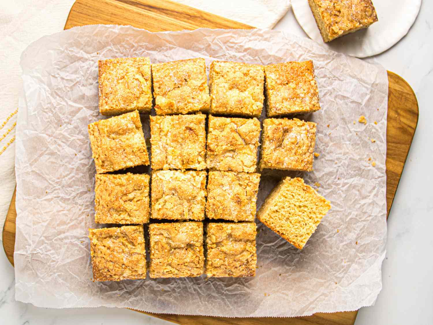 Cut square slices of cake arranged on parchment paper on a wooden board