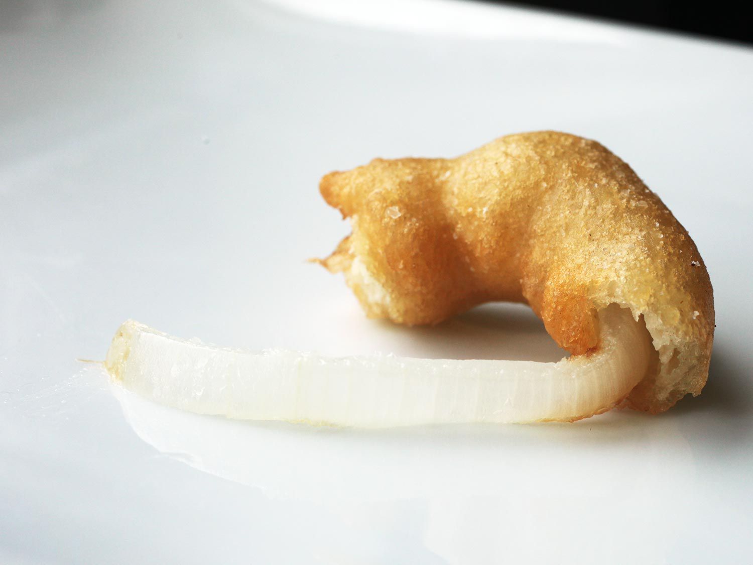 An undercooked onion ring that refused to yield to a bite. The still-firm onion flesh that resisted is still attached to the rest of the ring, naked and sad.