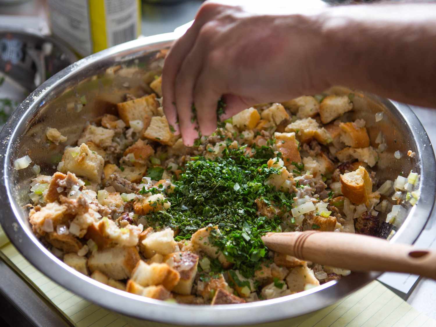Adding parsley to oyster stuffing ingredients in a mixing bowl.