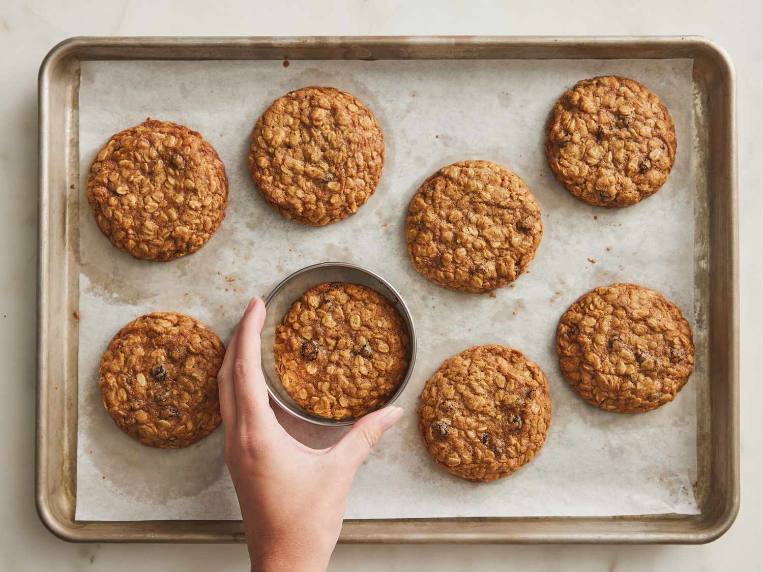 shaping baked cookies with a ring cutter on baking sheet 