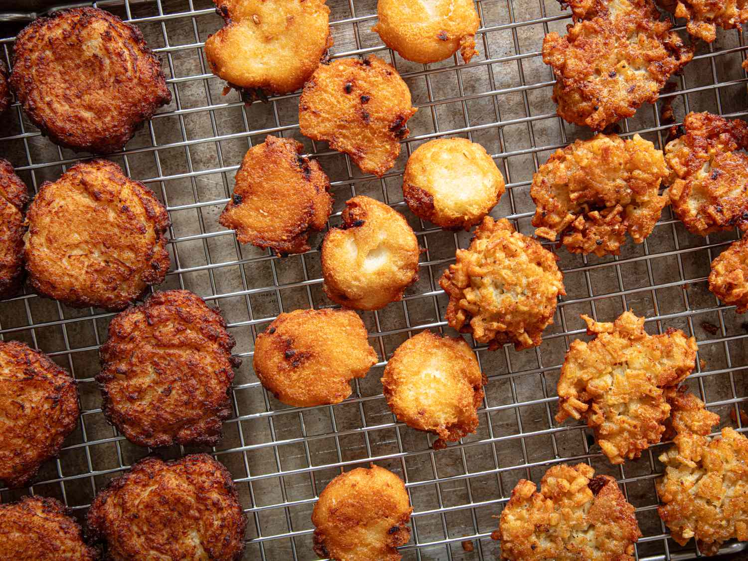 Assorted latkes cooling on a wire rack