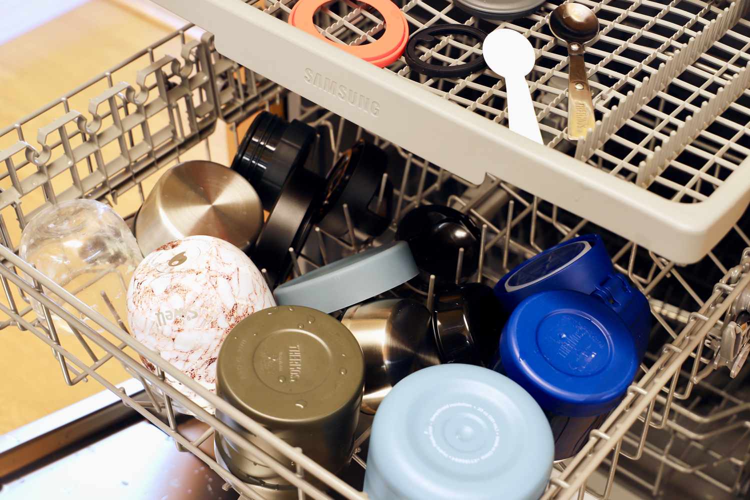 Thermoses in a dishwasher with gaskets and spoons separated 