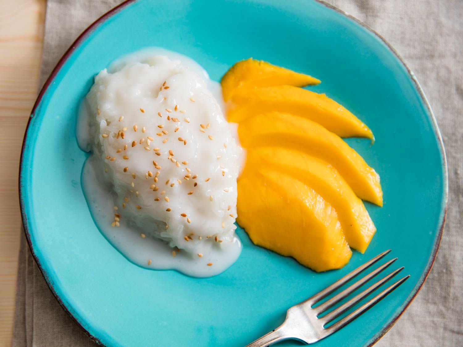 Overhead of coconut sticky rice on a plate with slices of mango.