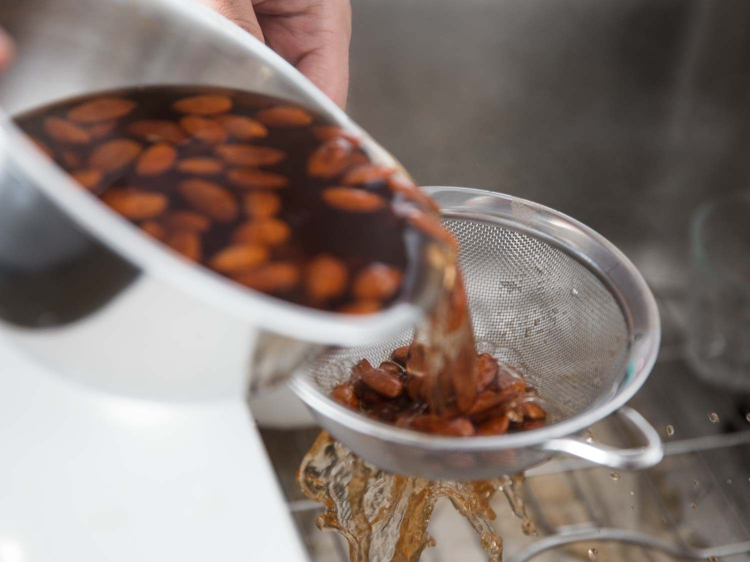 Steeped almonds are drained into a fine mesh strainer.