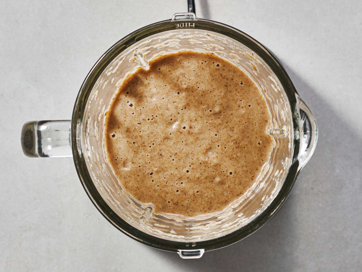 A batch of the soup, fully blended, inside of the bowl of a blender.