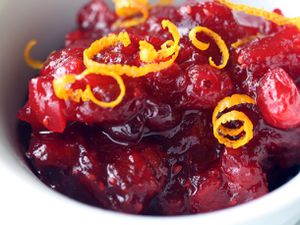 Cranberry chutney in a bowl topped with curls of shaved orange zest.