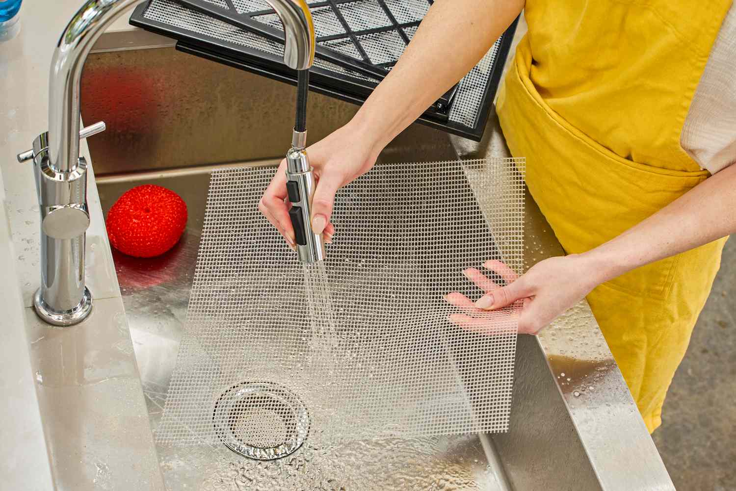A person washing the tray net of Excalibur Electric Food Dehydrator Machine