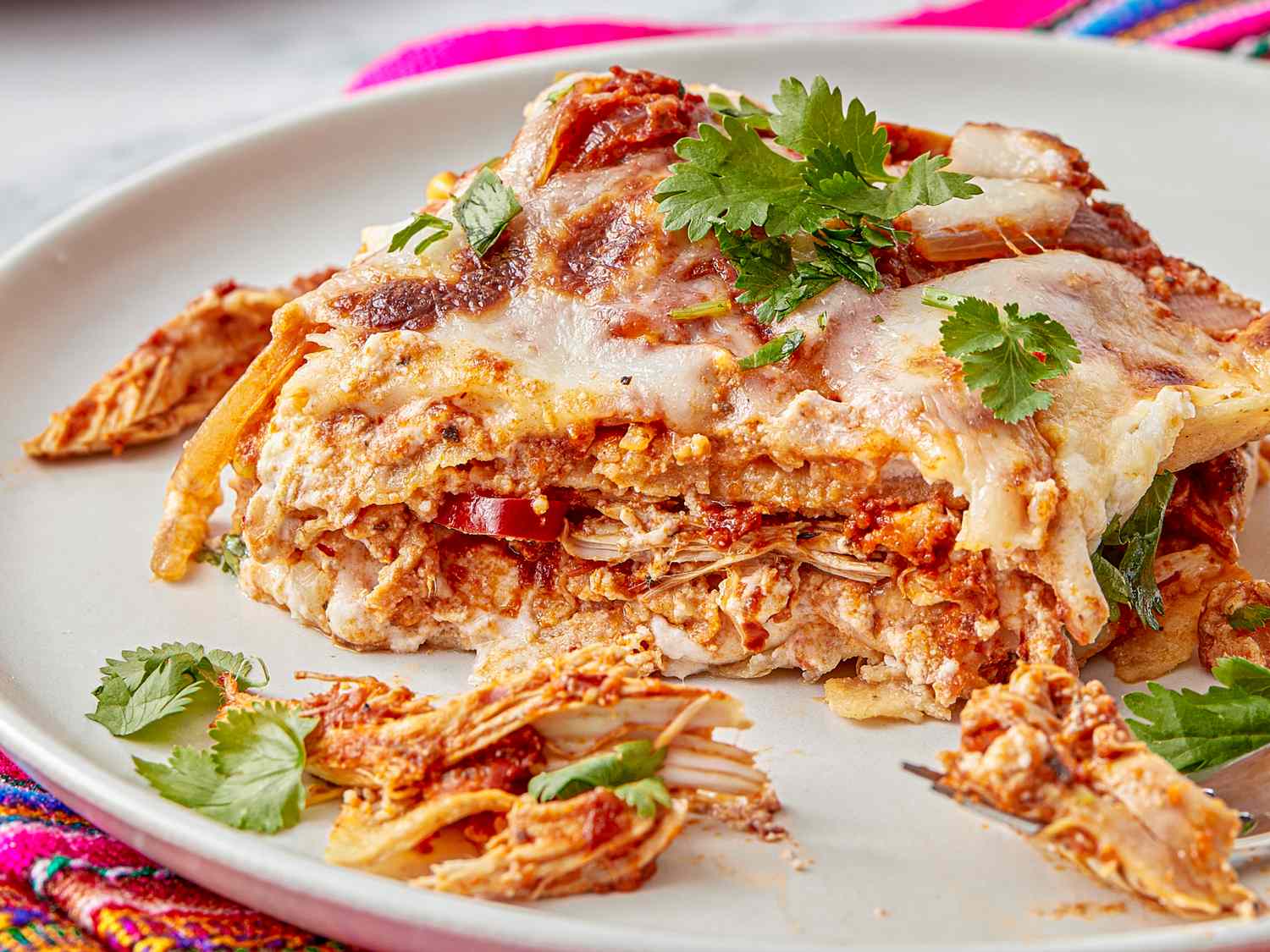 Mexican pastel azteca dish served on a plate garnished with fresh cilantro and melted cheese