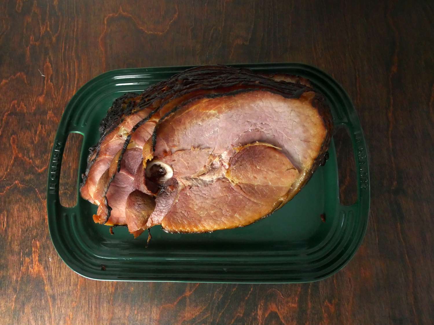 North country smokehouse ham on a green platter on a wooden surface