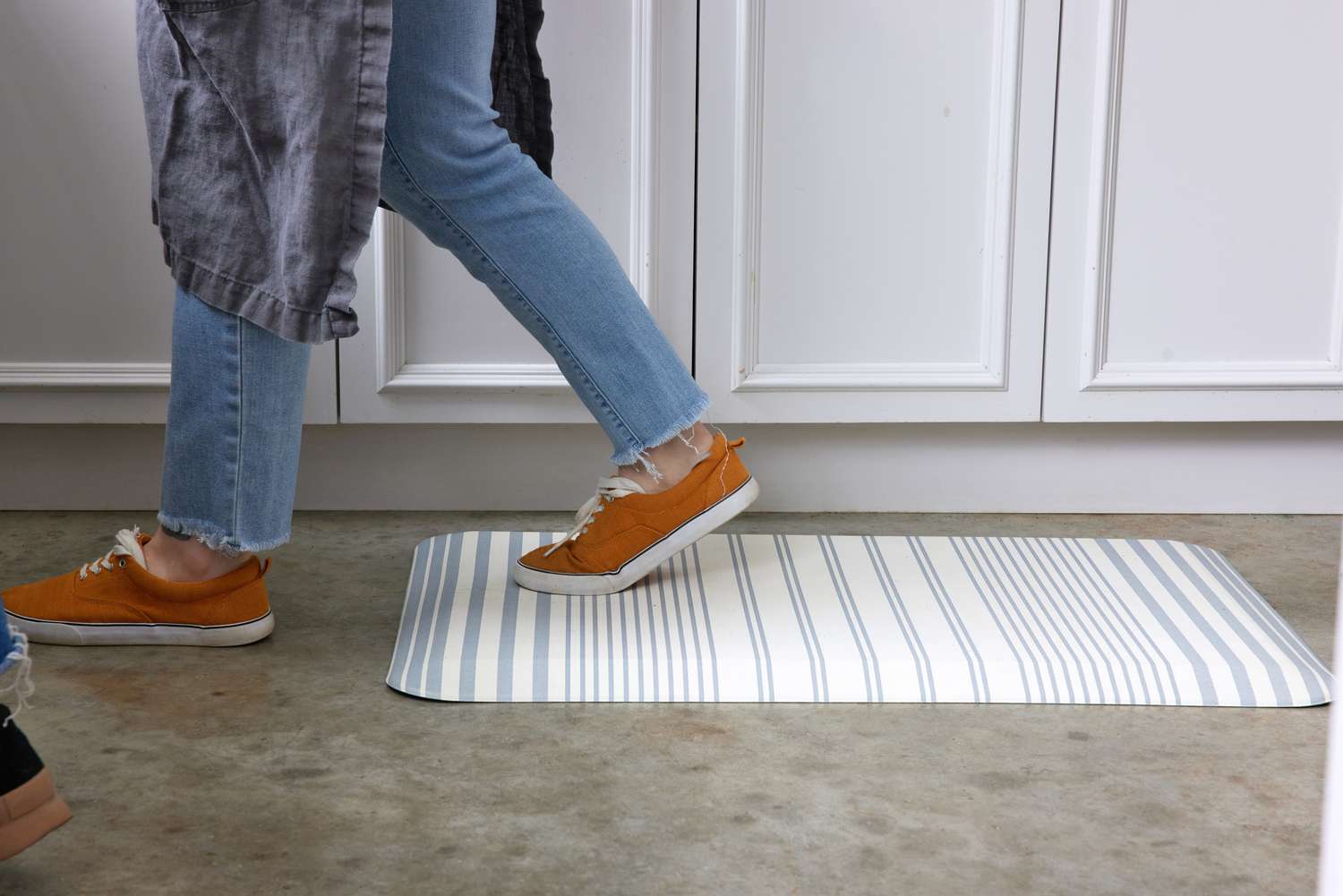 A person walking across a stripped anti-fatigue mat on a kitchen floor