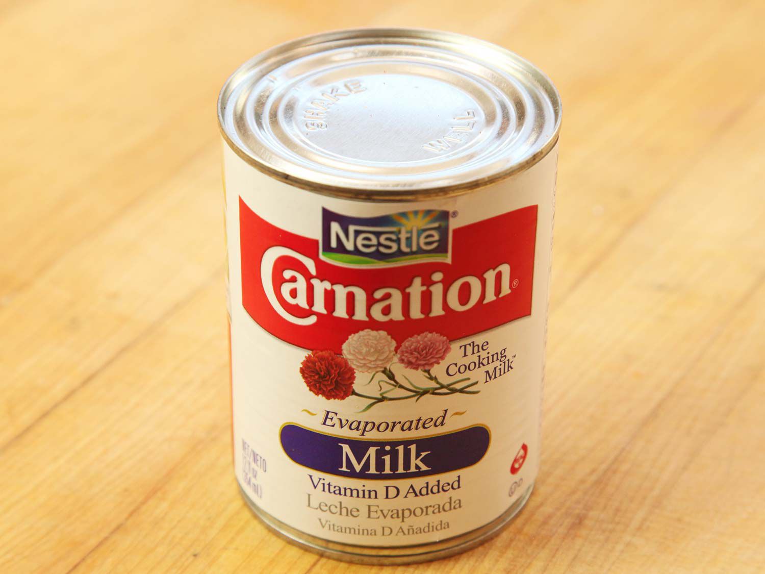 A can of evaporated milk on the cutting board. 