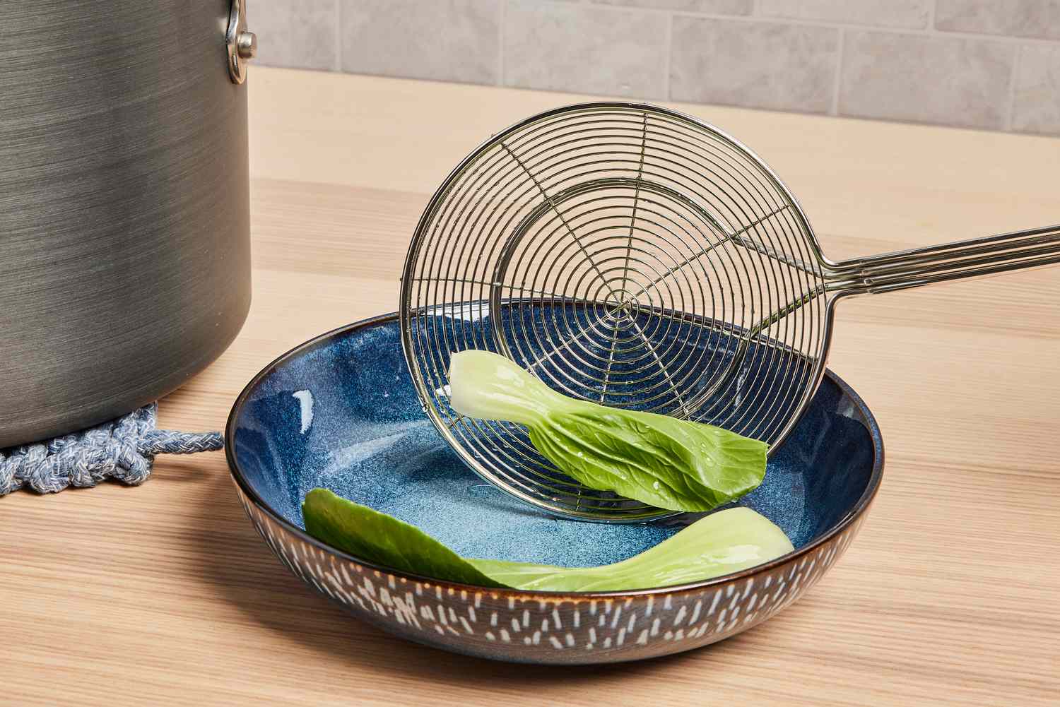 a spider skimmer depositing bok choy into a bowl
