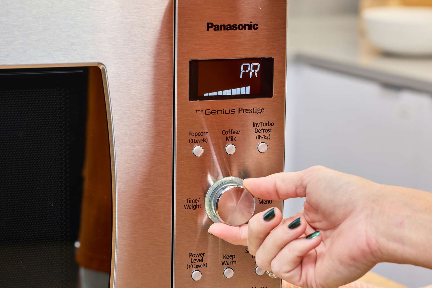 A hand turning a nob on the Panasonic - 2.2 Cu. Ft. 1250 Watt SD987SA Full-Size Microwave with Inverter