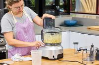 A person uses the Breville 16-Cup Sous Chef Peel & Dice Food Processor to chop food