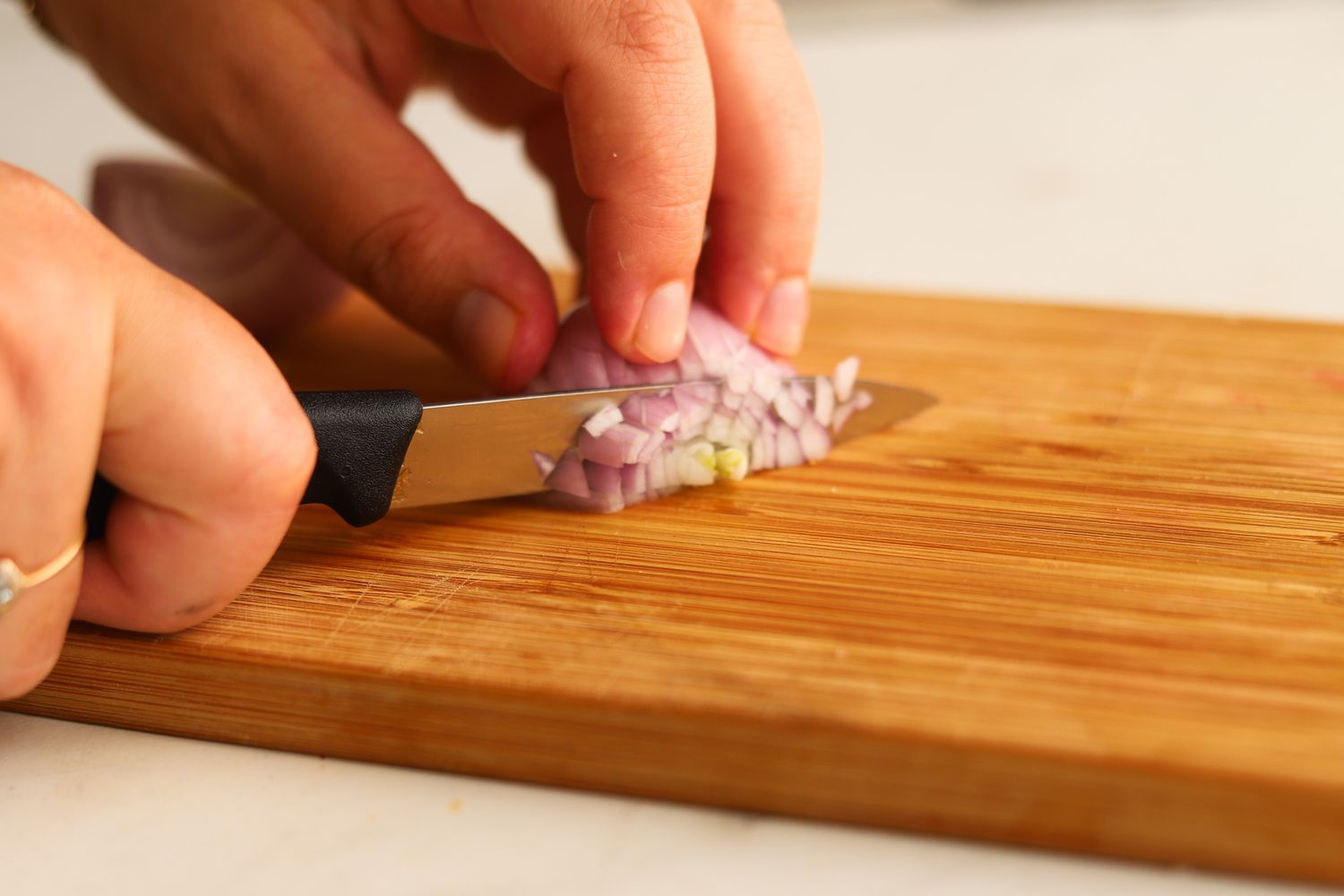 A small paring knife slicing a shallot.