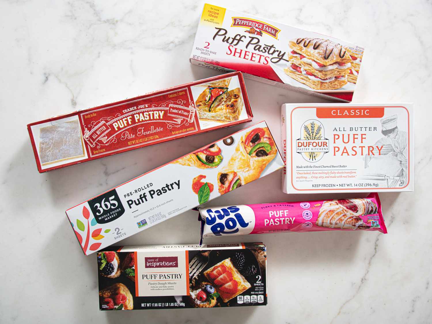 An assortment of puff pastry packaging arranged on a surface representing different brands