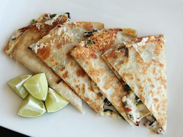 Ramp and chorizo quesadillas cut in wedges on a plate with lime wedges.