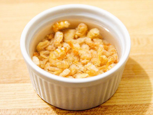 Dried shrimp being soaked in a ramekin of water. 