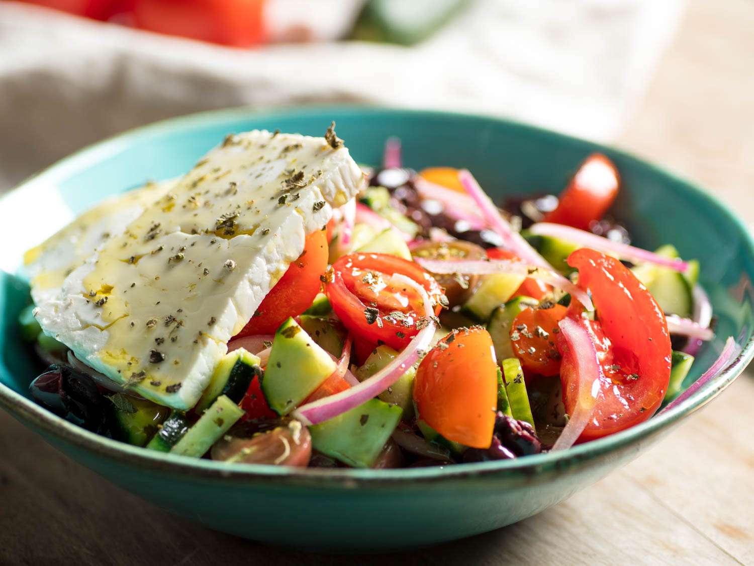 A finished Greek salad, with ripe tomatoes and a slab of salty feta.