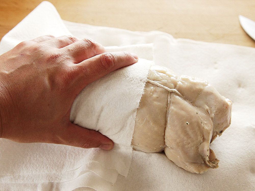patting dry turkey porchetta with paper towel