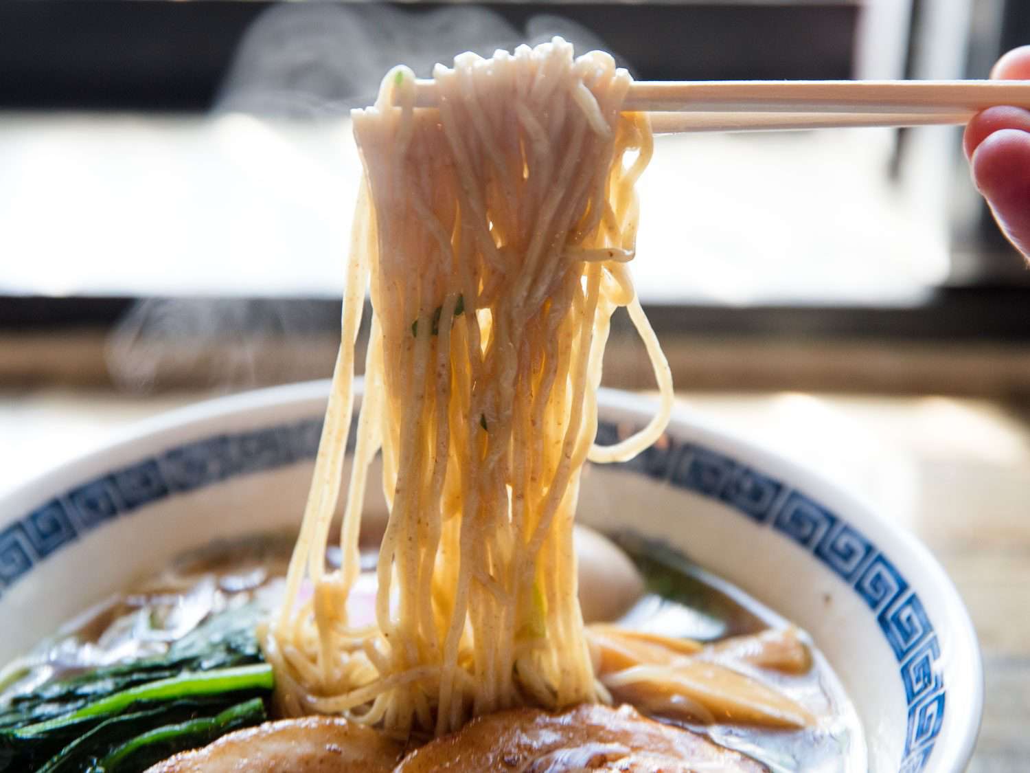 Noodles being pulled out of bowl of shoyu ramen at Ramen Shack