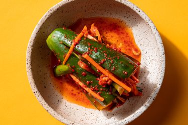 Overhead of a piece of stuffed cucumber kimchi in a small serving bowl.