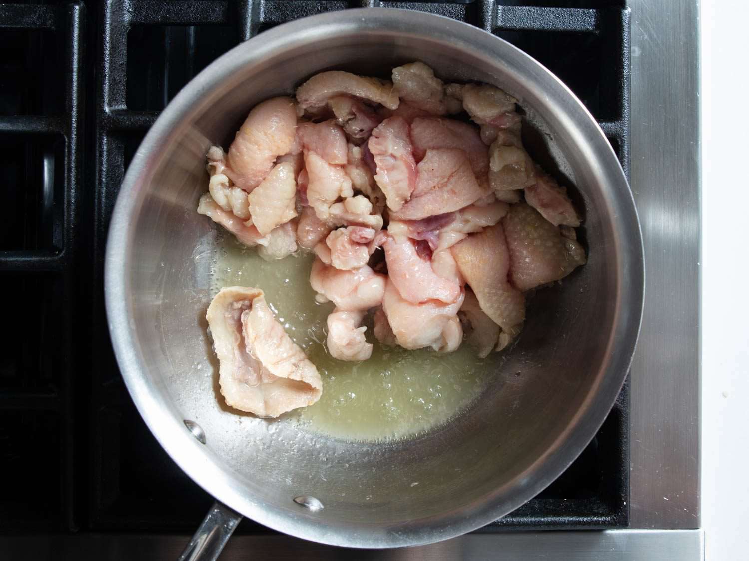 Overhead of duck fat in a saucepan with a little water.