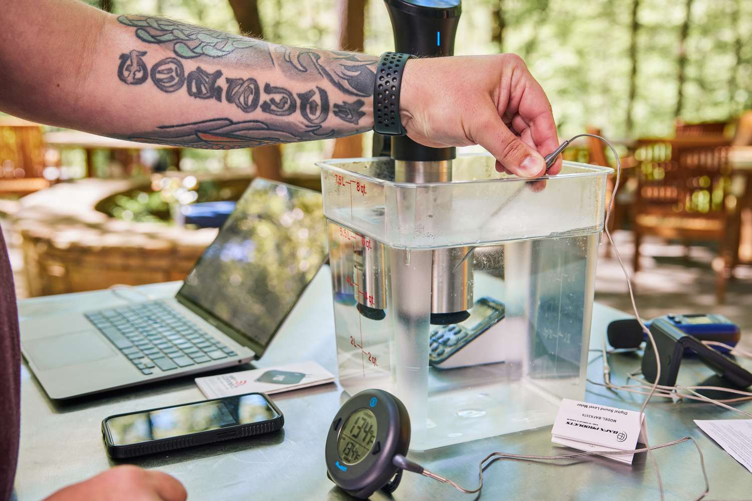 a person taking the temperature of a sous vide water bath with a thermometer