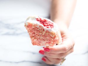 Closeup of a Strawberry Shortcake Ice Cream Bar, held upright for the camera by the author. A bite has been taken, revealing the swirled strawberry interior.