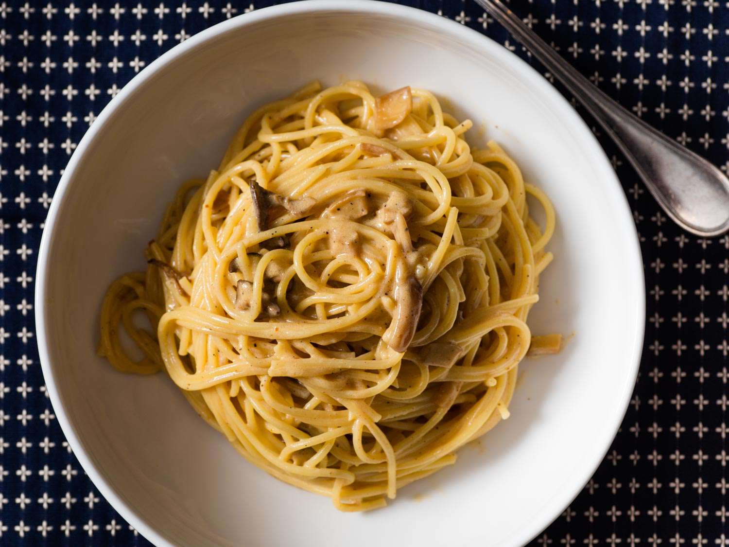 Overhead shot of a white pasta bowl with a healthy serving of vegan pasta carbonara.